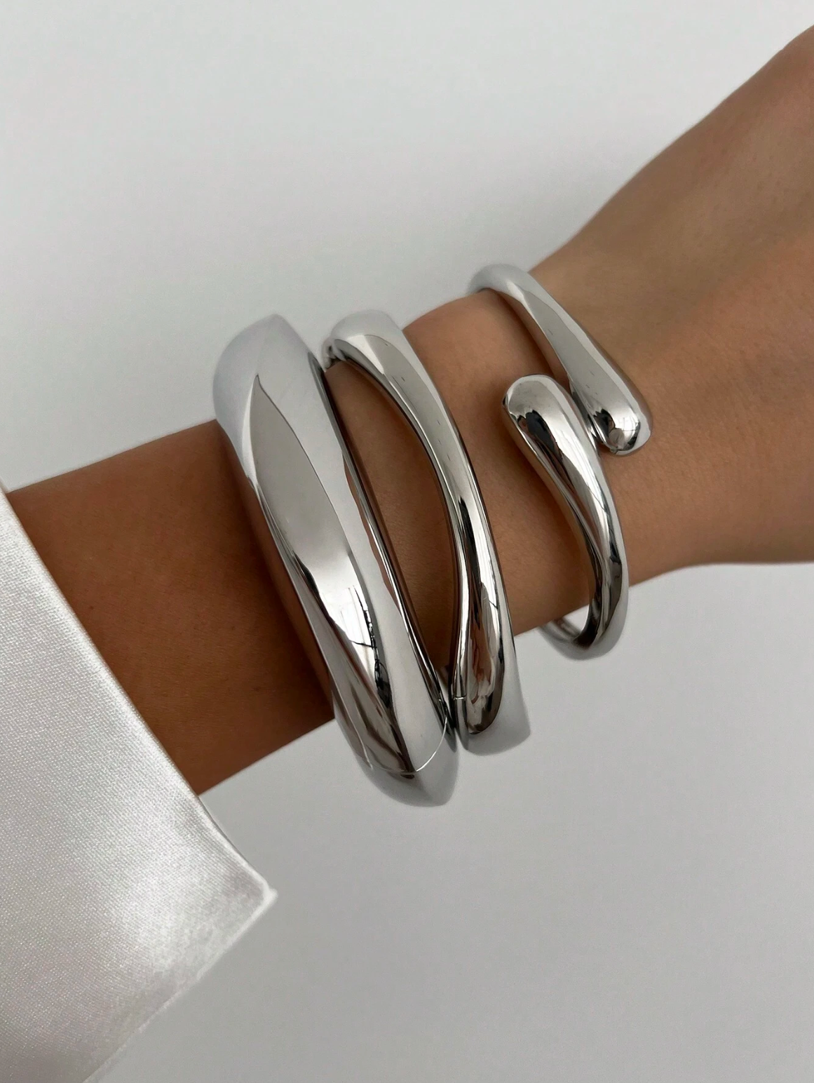 Modellen bär tredelat chunky armband i silver.