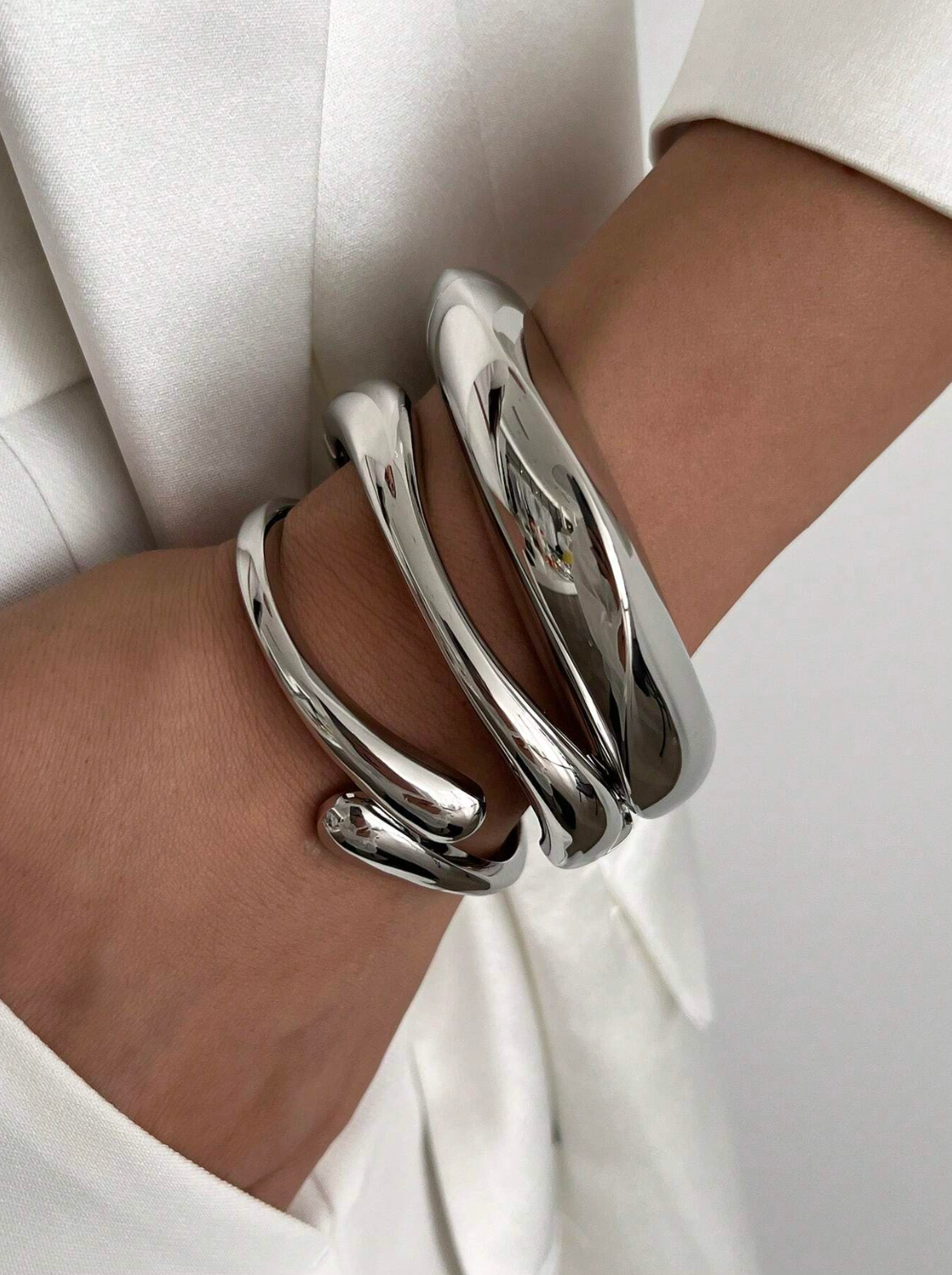 Modellen bär tredelat chunky armband i silver.